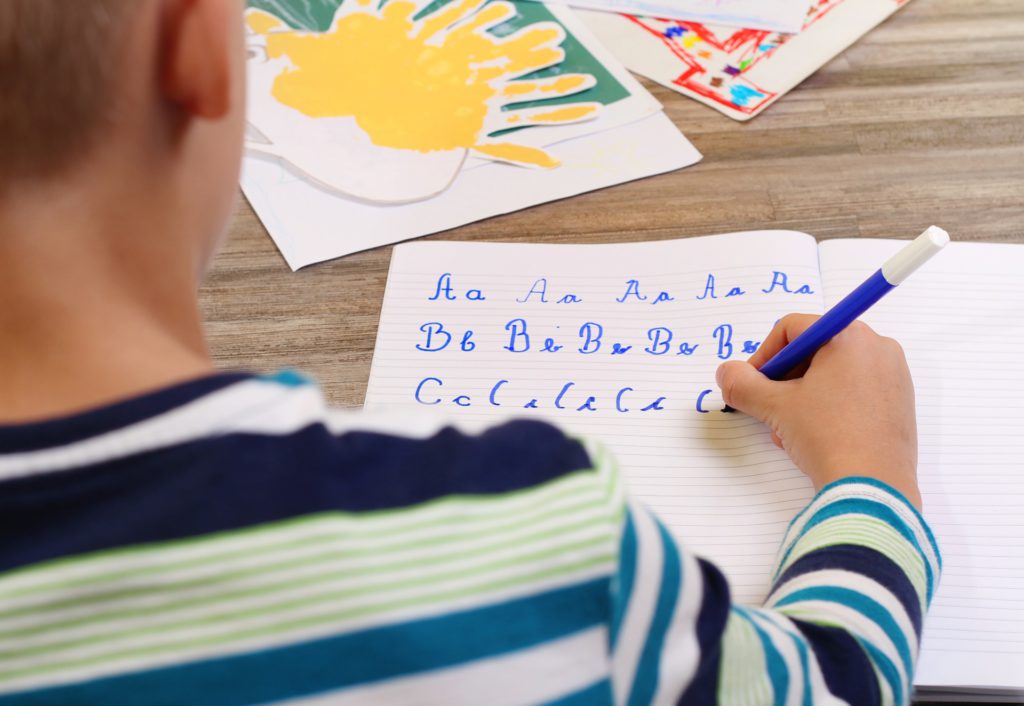 foto de criança escrevendo o alfabeto no papel