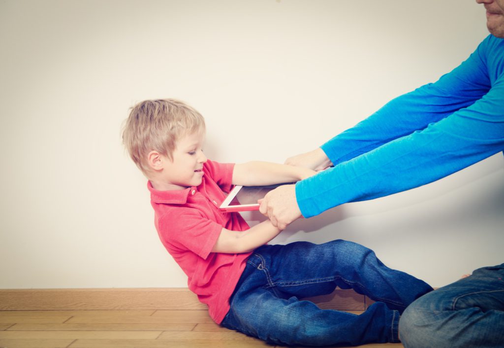 foto de criança tirando tablet da mão do pai